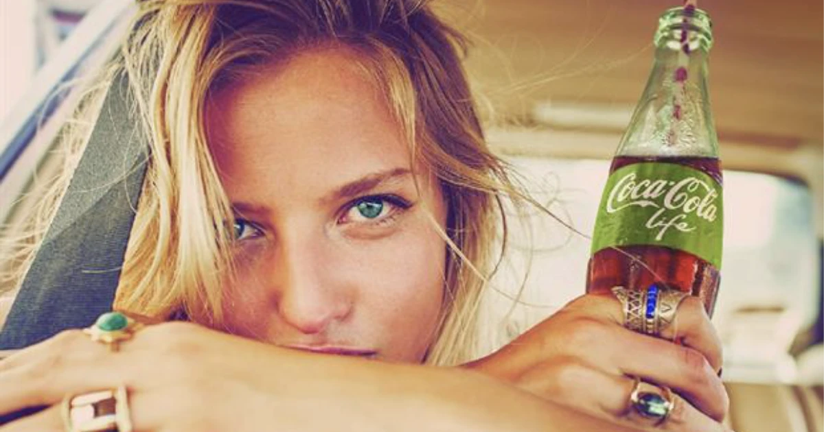 The Coca-Cola Company Woman holding a green-label Coca-Cola Life glass bottle in an advert