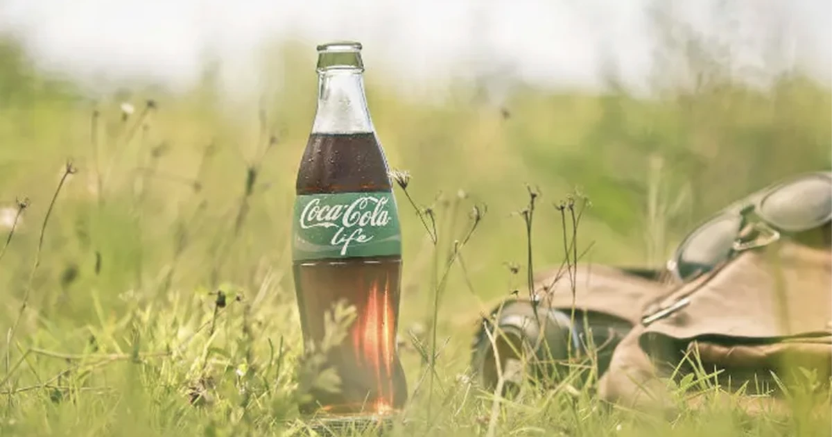 The Coca-Cola Company Coca-Cola Life bottle in grass beside sunglasses