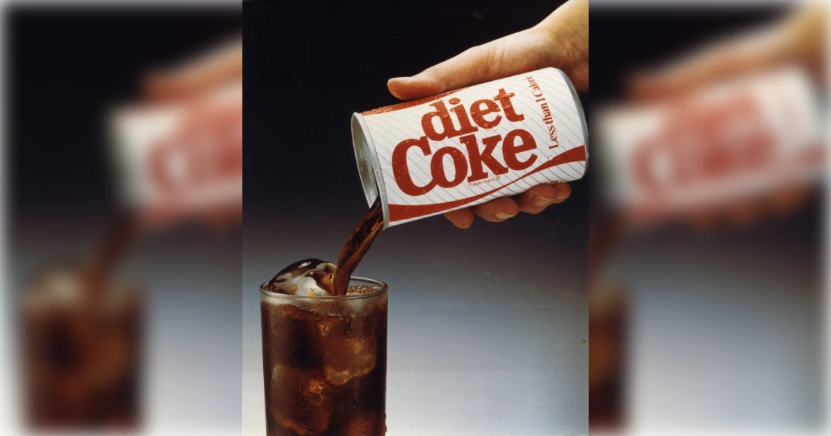 Hand pouring a vintage Diet Coke can into a glass of ice