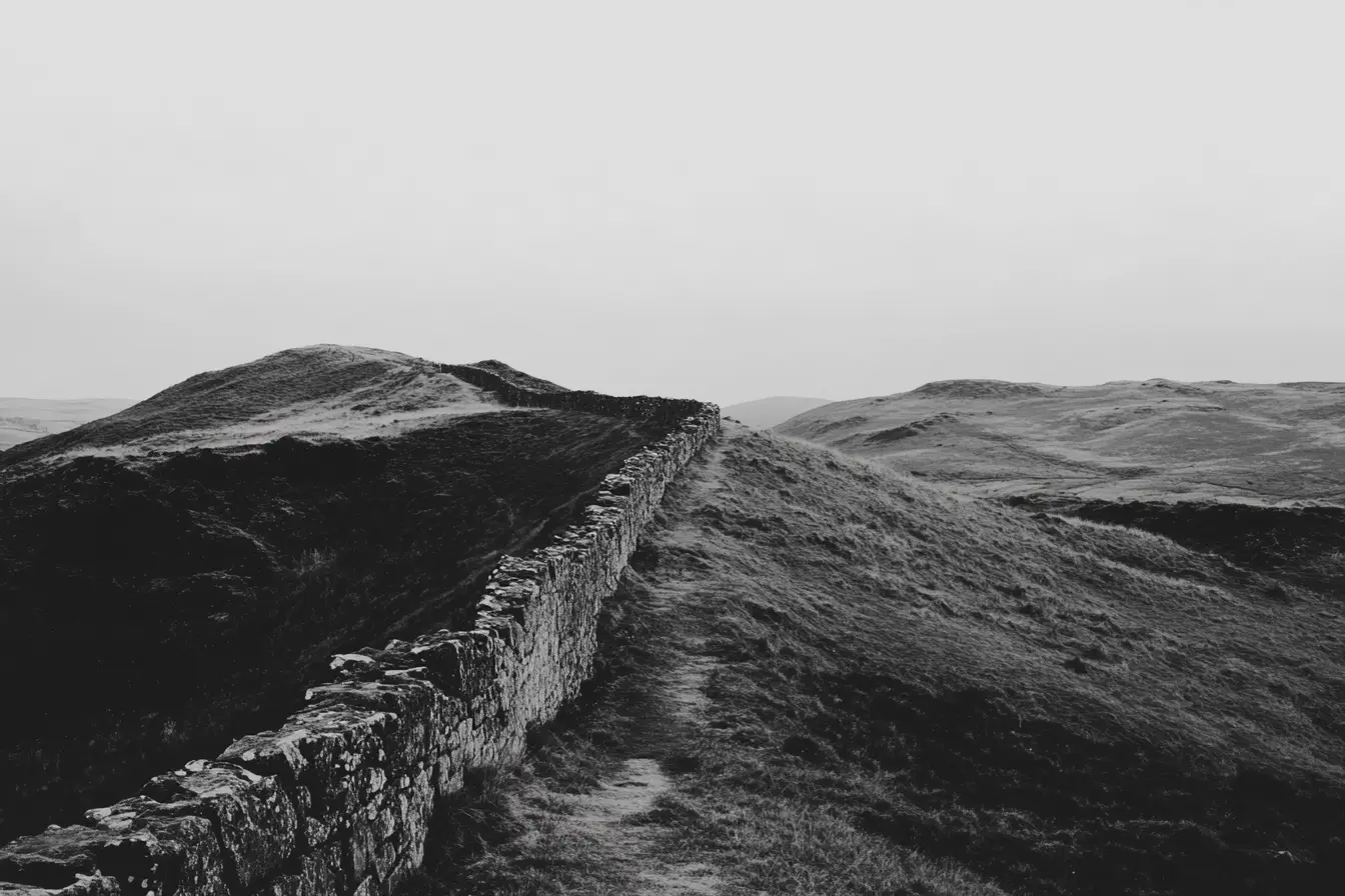 Hadrian's Wall across the hills © History Oasis Hadrian's Wall stone rampart crossing rolling hills in black and white