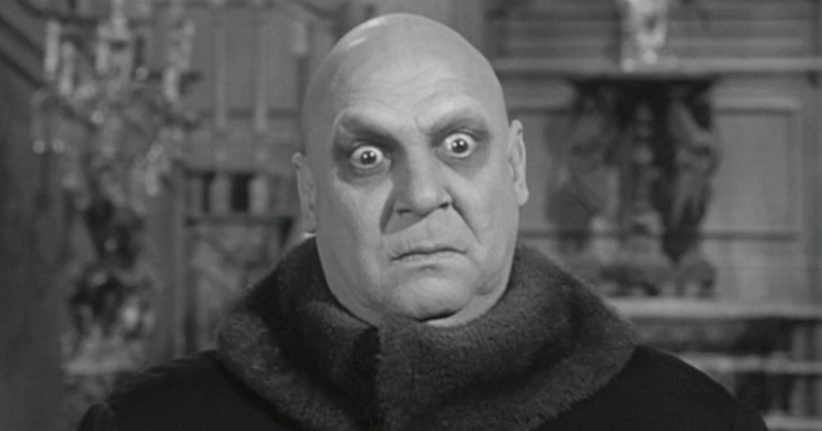 Uncle Fester, bald wide-eyed man in fur collar, black-and-white still