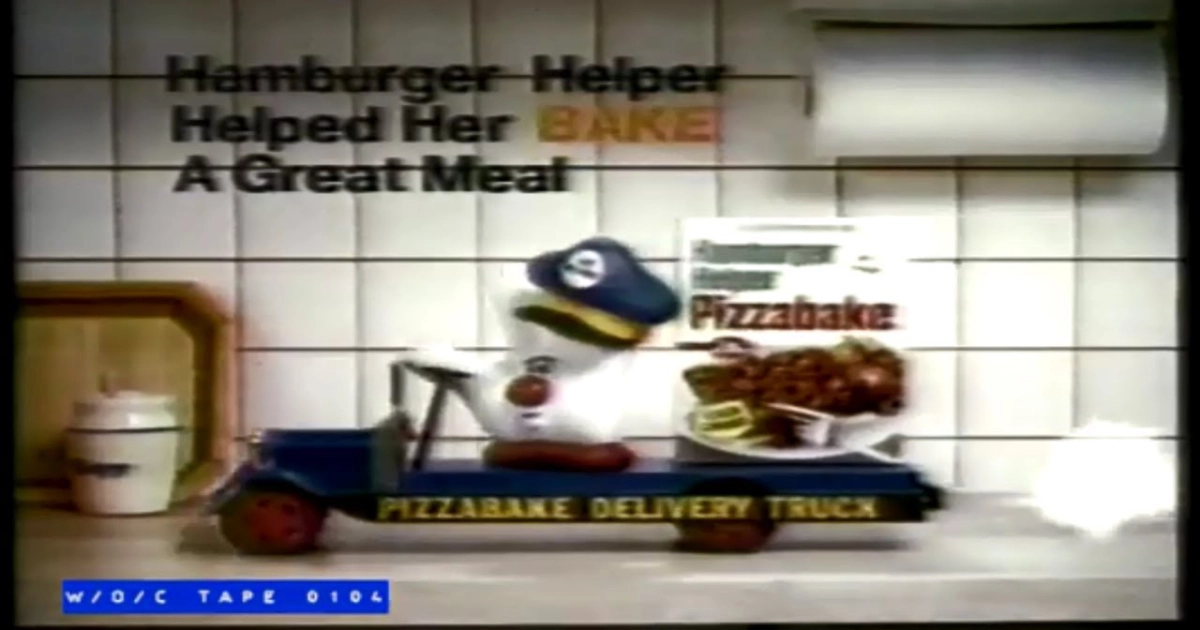 Still from a 1980s Hamburger Helper Pizzabake TV commercial with the mascot driving a Pizzabake Delivery Truck