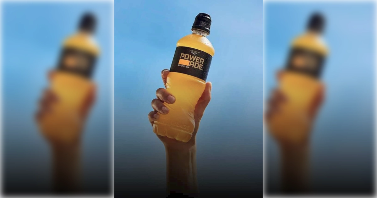The Coca-Cola Company Hand raising gold Powerade Gold Rush bottle against blue sky