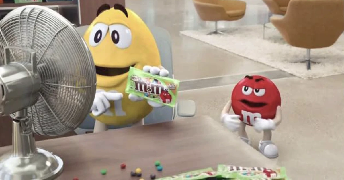 Yellow and Red M&M's characters holding a green Crispy M&M's bag