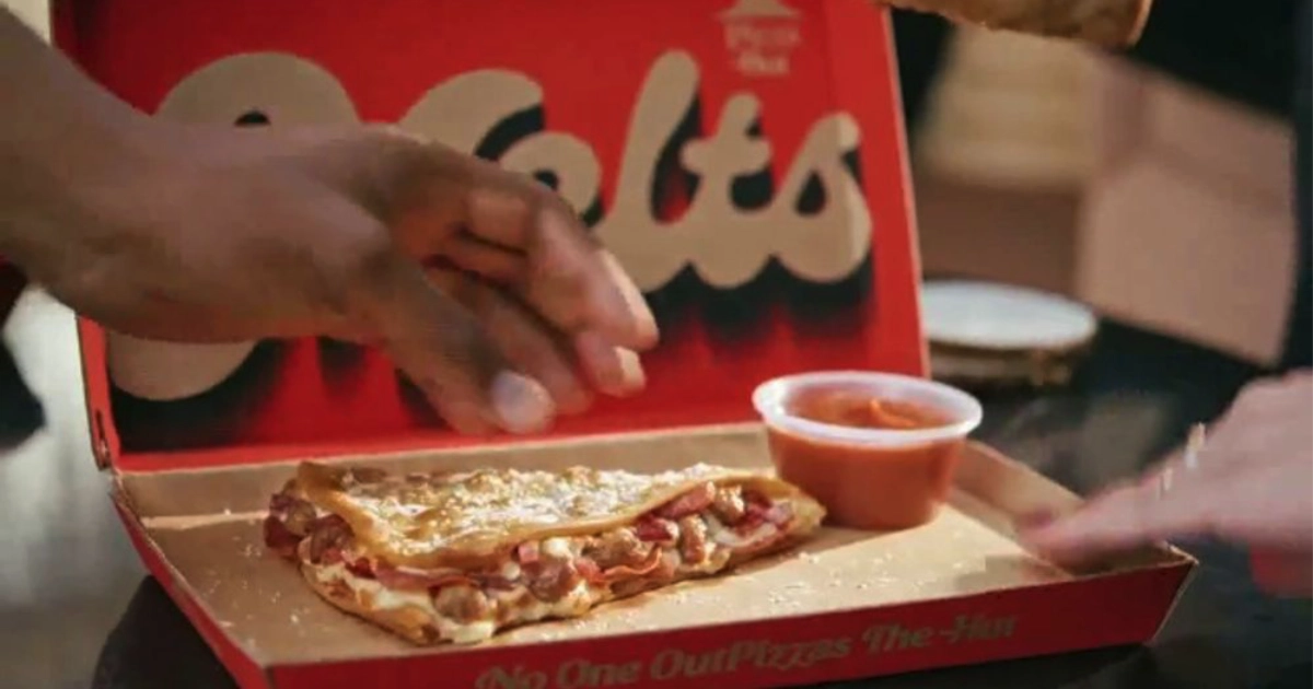 Pizza Hut Hand lifting a folded Pizza Hut Melt from red box with marinara cup