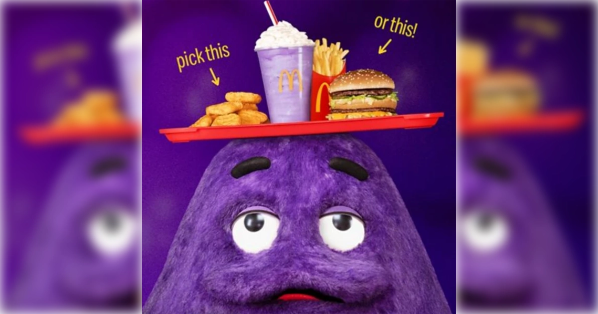 Grimace pitching the menu after his redesign from “Evil Grimace” — McDonald's The purple McDonald's mascot Grimace holding a tray with a milkshake, fries and a burger