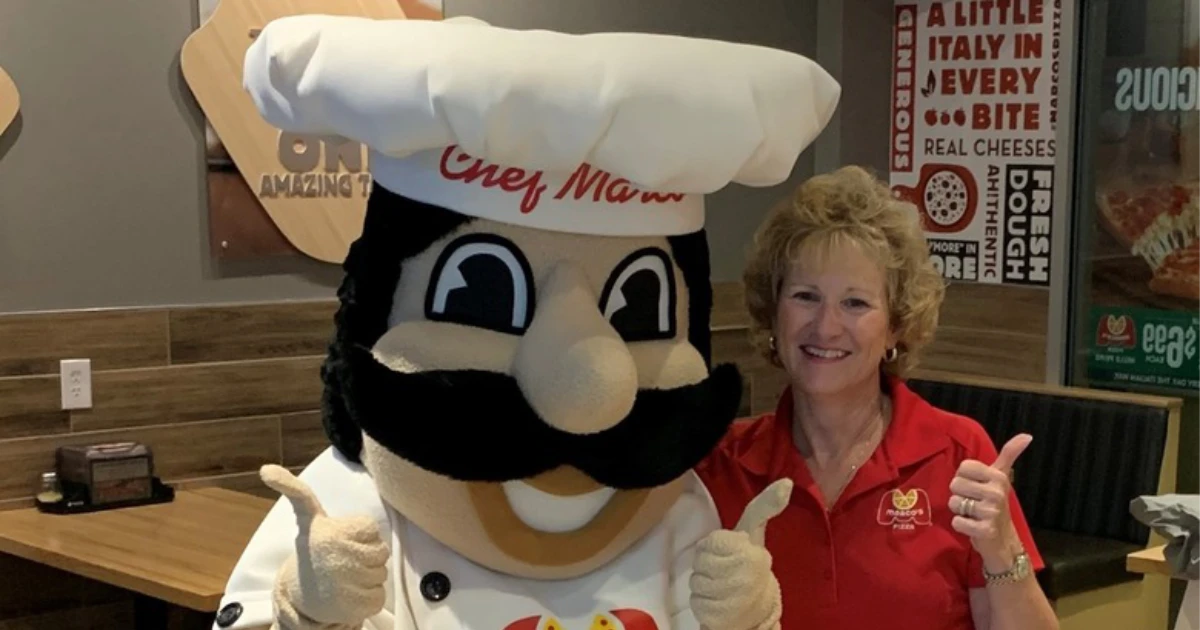 Chef Marco, drawn from founder Pat Giammarco, at a store appearance — Marco's Pizza The costumed Chef Marco mascot in a white chef's hat giving a thumbs-up beside a Marco's Pizza employee