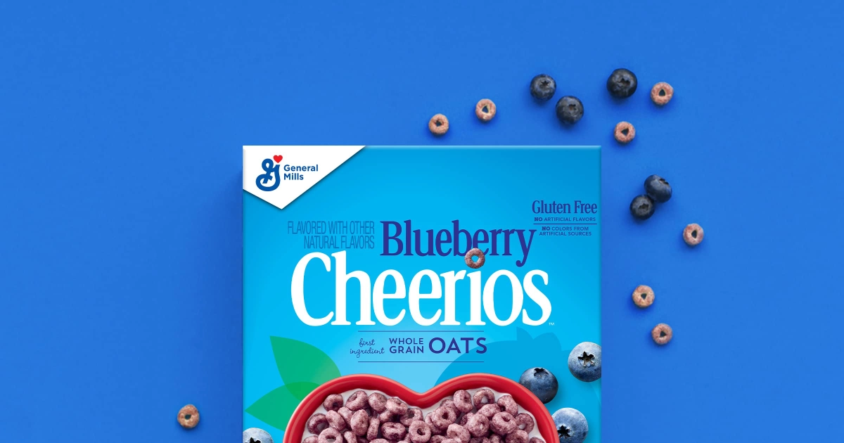 General Mills Blueberry Cheerios box on blue background with scattered rings and blueberries