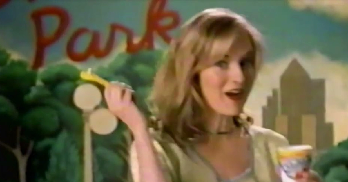 Woman holding a yogurt cup and spoon in a vintage TV commercial