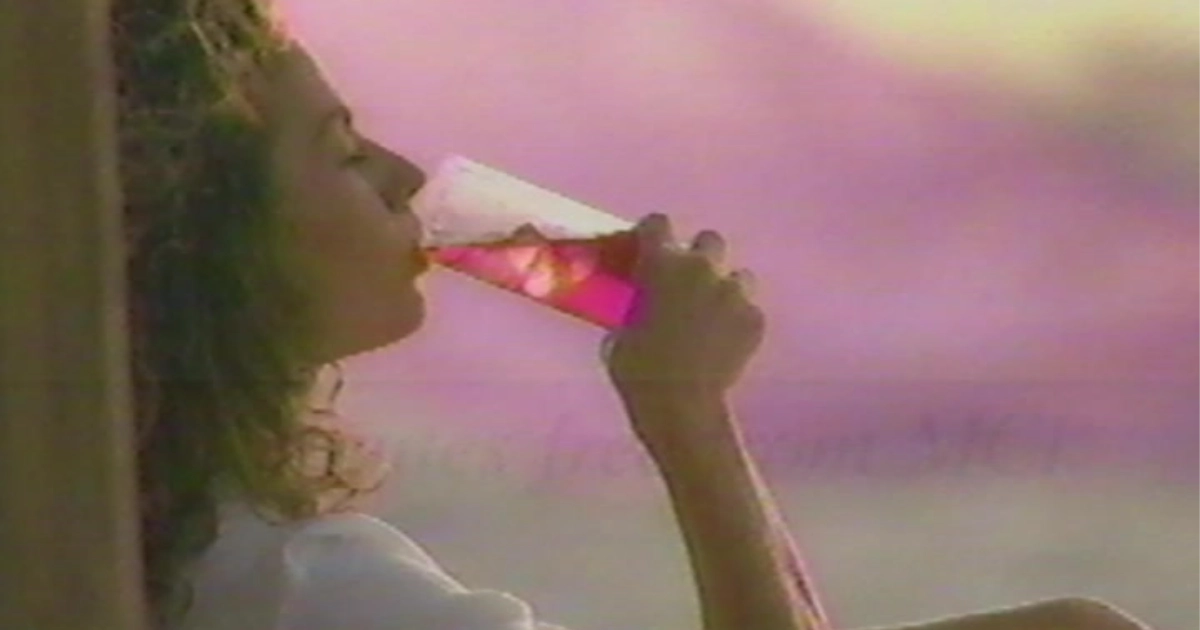 Woman drinking a pink beverage in a vintage Crystal Light TV commercial still