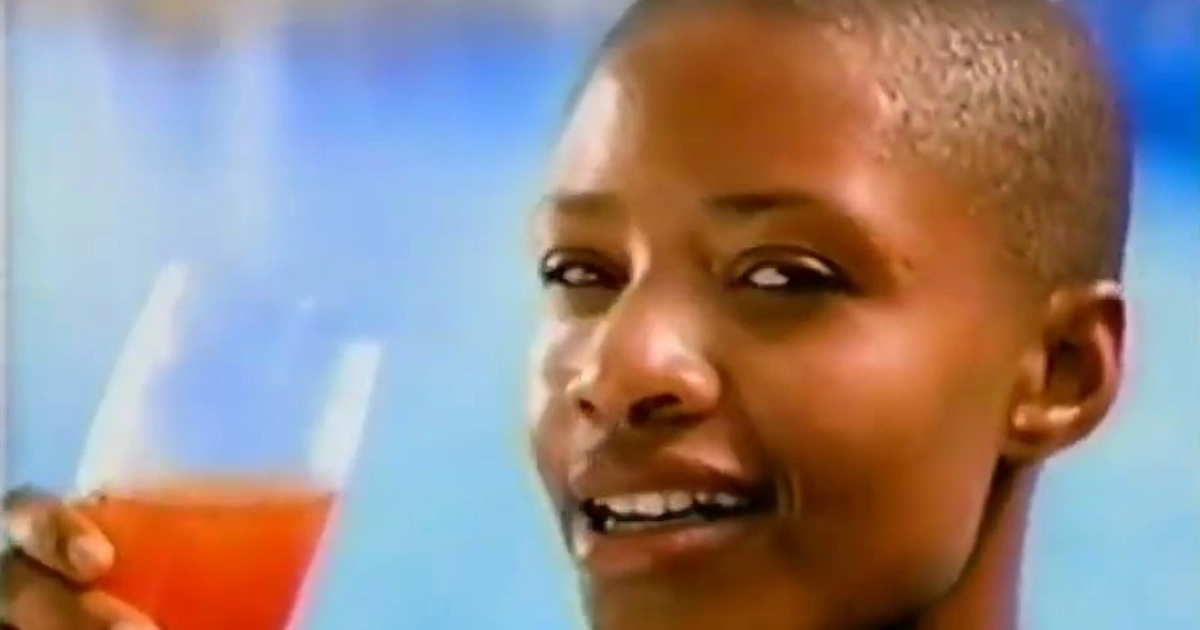 Smiling woman holding a glass of orange drink, vintage Crystal Light commercial still