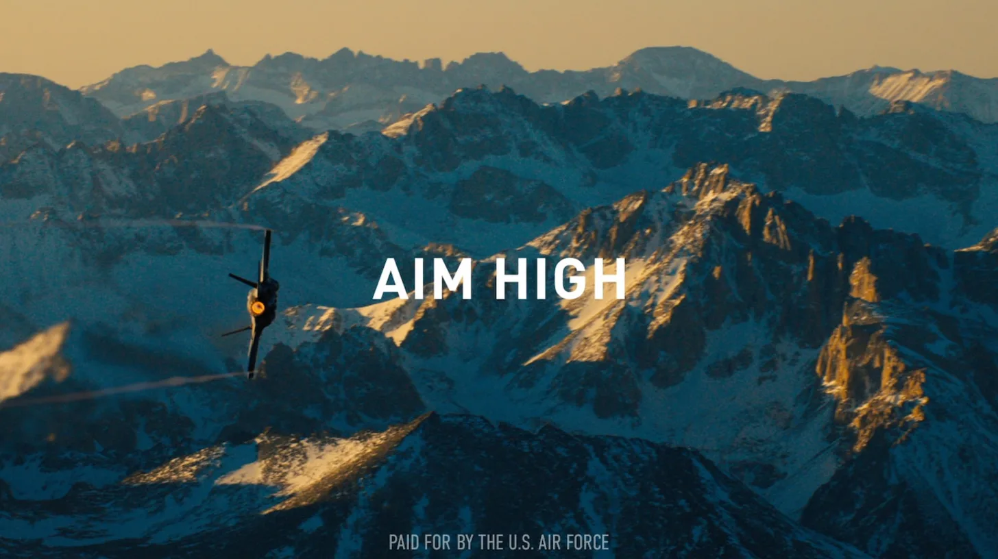 Aim High over the mountains in a recent recruiting ad / U.S. Air Force Aim High recruiting ad with a fighter jet banking over snowy mountain peaks at sunset