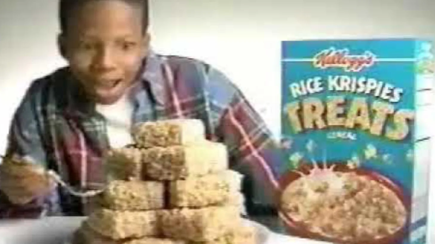 Excited kid behind a towering plate of Rice Krispies Treats squares next to the blue Kellogg's Rice Krispies Treats Cereal box in a 1995 TV commercial