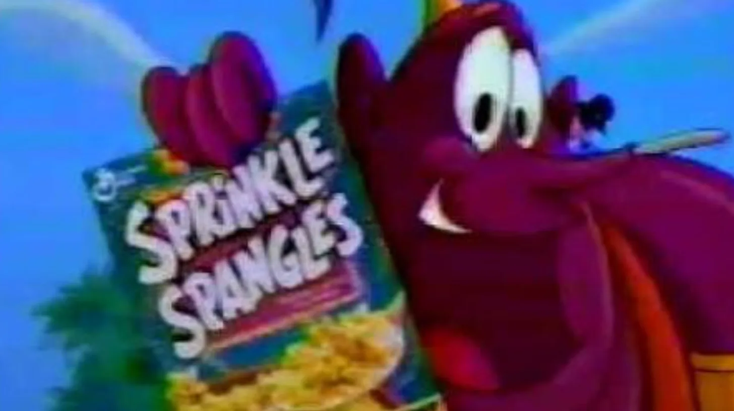 The purple Sprinkle Genie mascot grinning beside a box of General Mills Sprinkle Spangles cereal in a 1990s TV commercial
