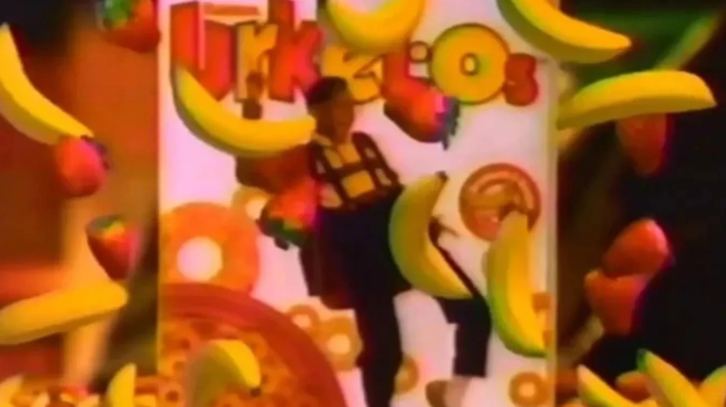 Steve Urkel in suspenders dancing in front of a giant Urkel-Os cereal box as bananas and strawberries fly through the air in the 1991 TV commercial