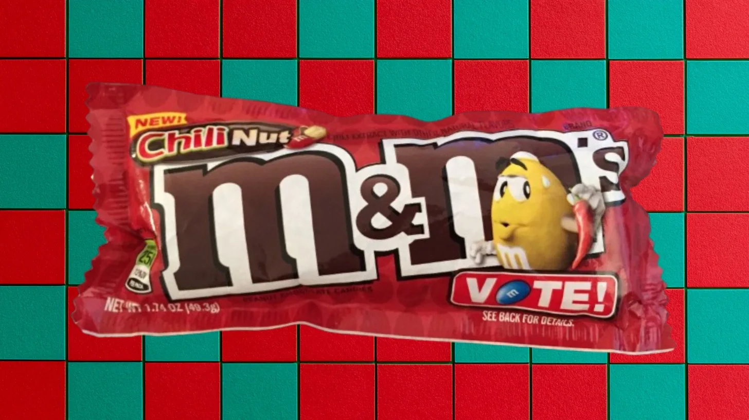 A Chili Nut M&M’s bag from the 2016 Flavor Vote — Mars, Inc. Red bag of Chili Nut M&M’s with the yellow M&M holding a chili pepper and a Vote badge