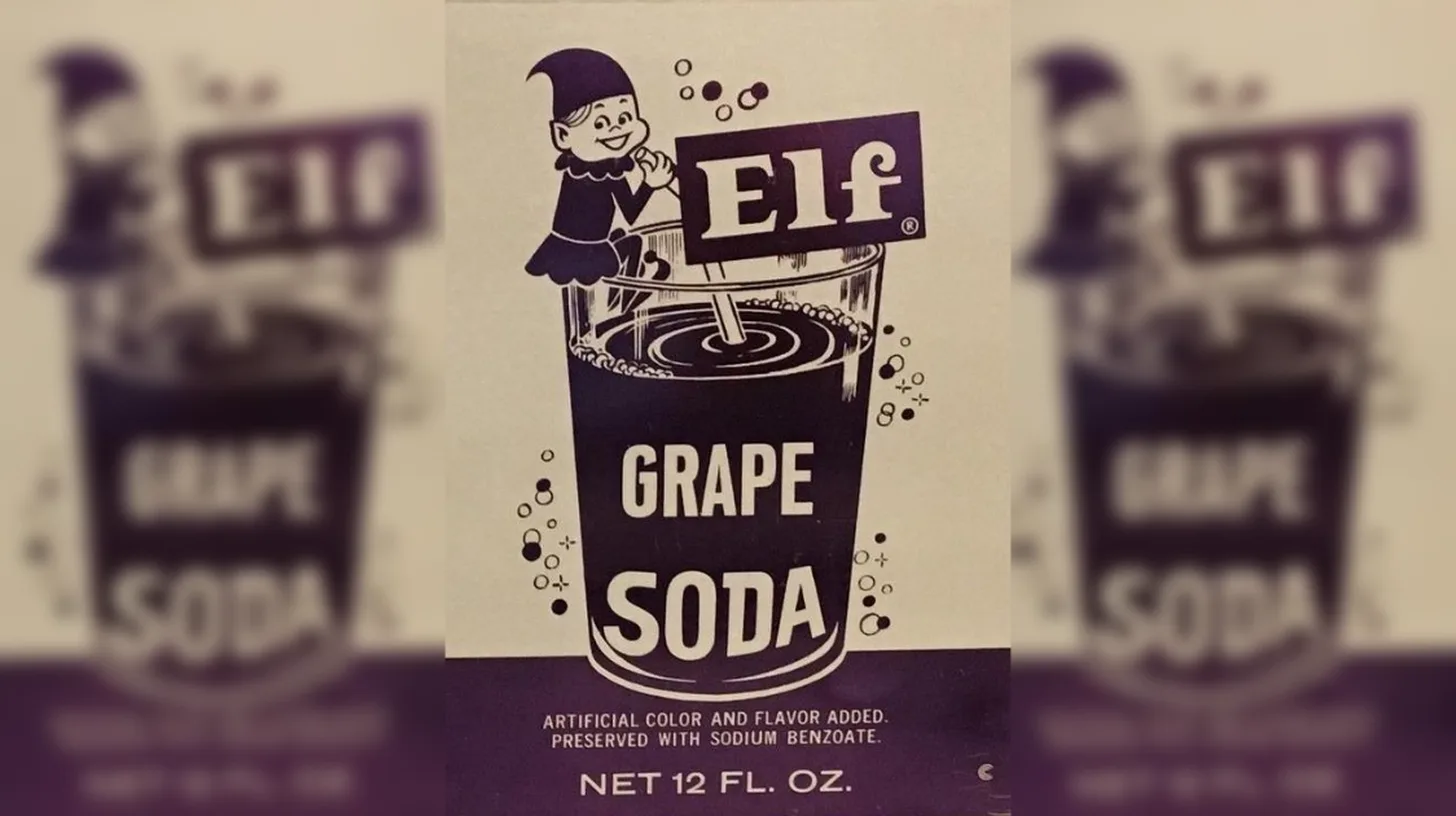 Elf Grape Soda packaging with a cartoon elf mascot leaning on the logo above a bubbling glass