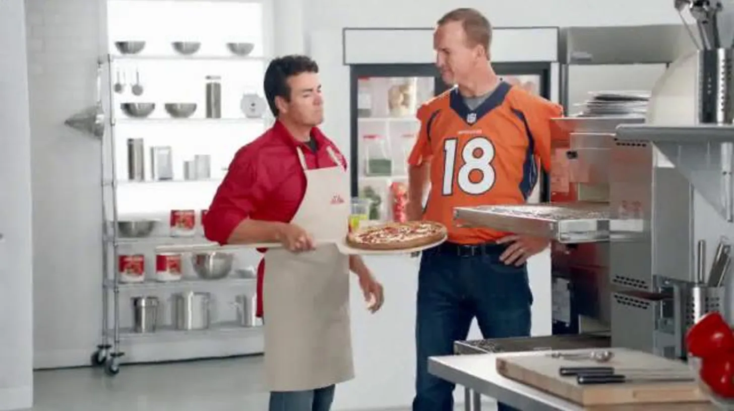John Schnatter and Peyton Manning in a Broncos-era commercial / Papa John's John Schnatter and Peyton Manning with a pizza in a Papa John's commercial kitchen