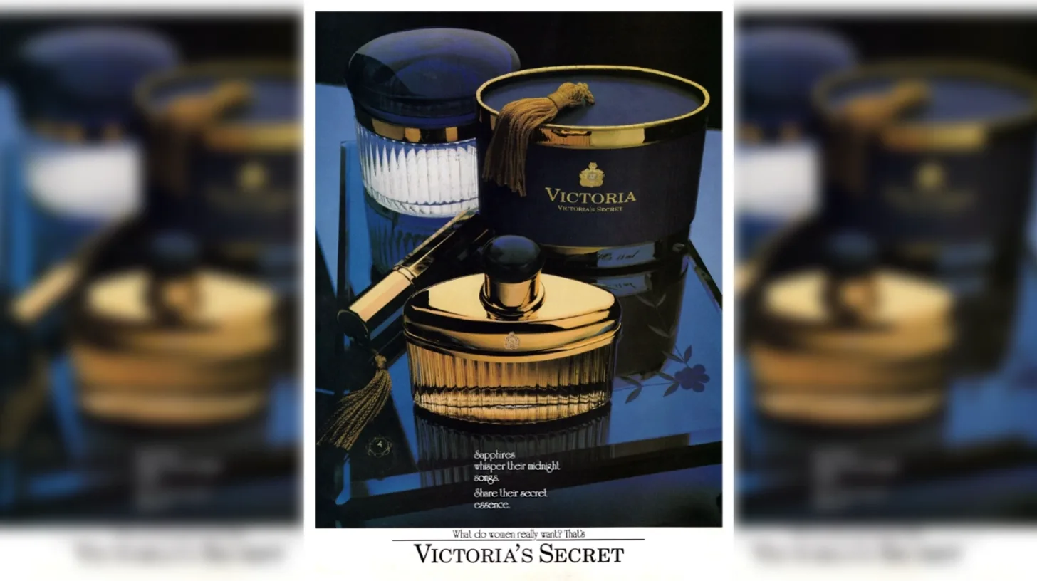 A Victoria's Secret print ad for the Victoria fragrance, showing navy and gold bottles with a tassel on a mirrored tray